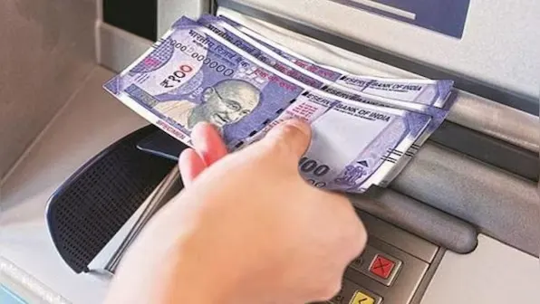 Hand withdrawing cash (INR notes) from an ATM