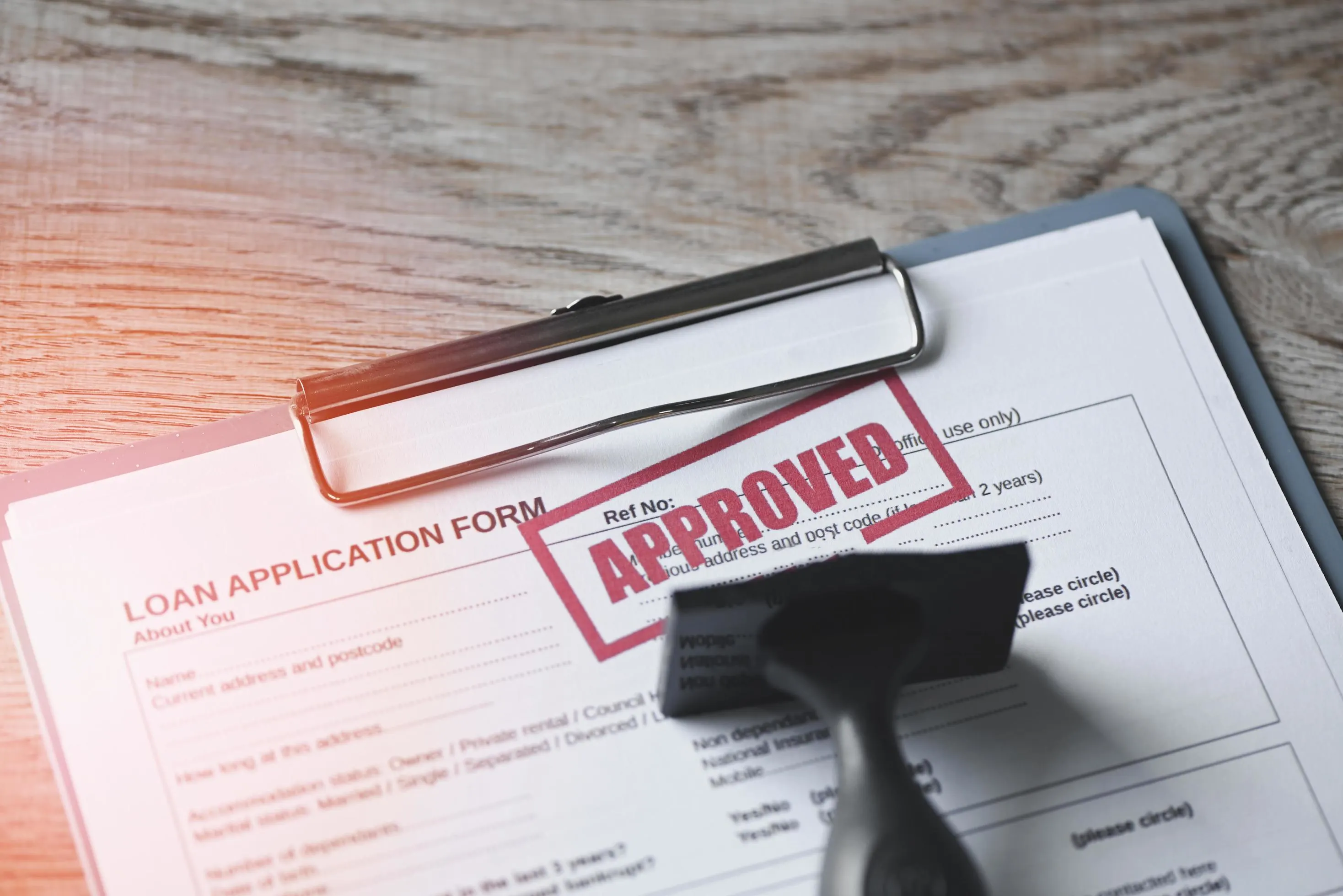 Document with approved stamp, pen, and small chalkboard, symbolizing loan approval